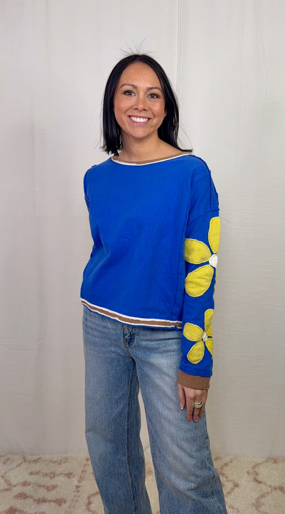Blue long sleeve top with floral appliqué sleeves worn with blue jeans