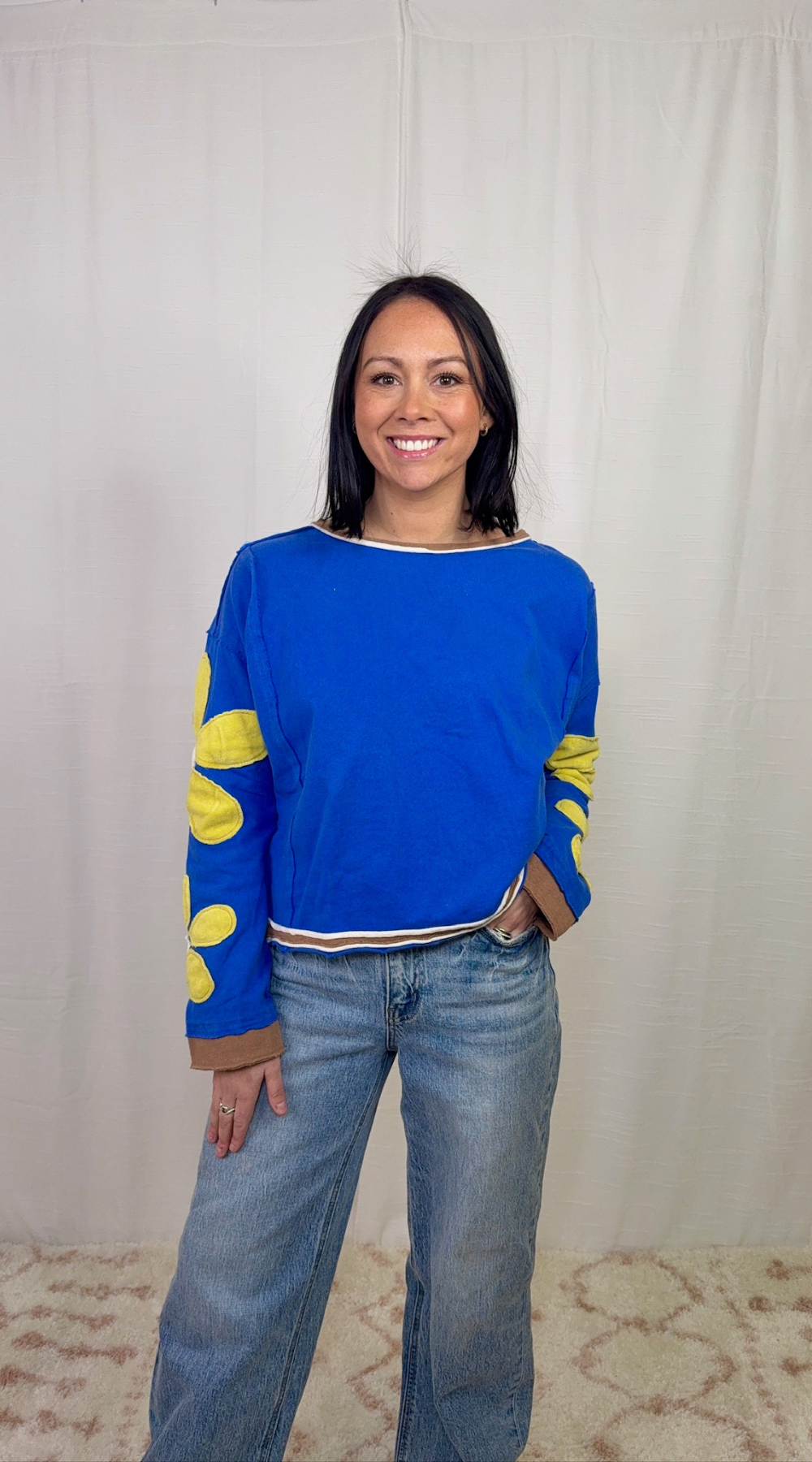 Blue long sleeve top with floral appliqué sleeves worn with blue jeans
