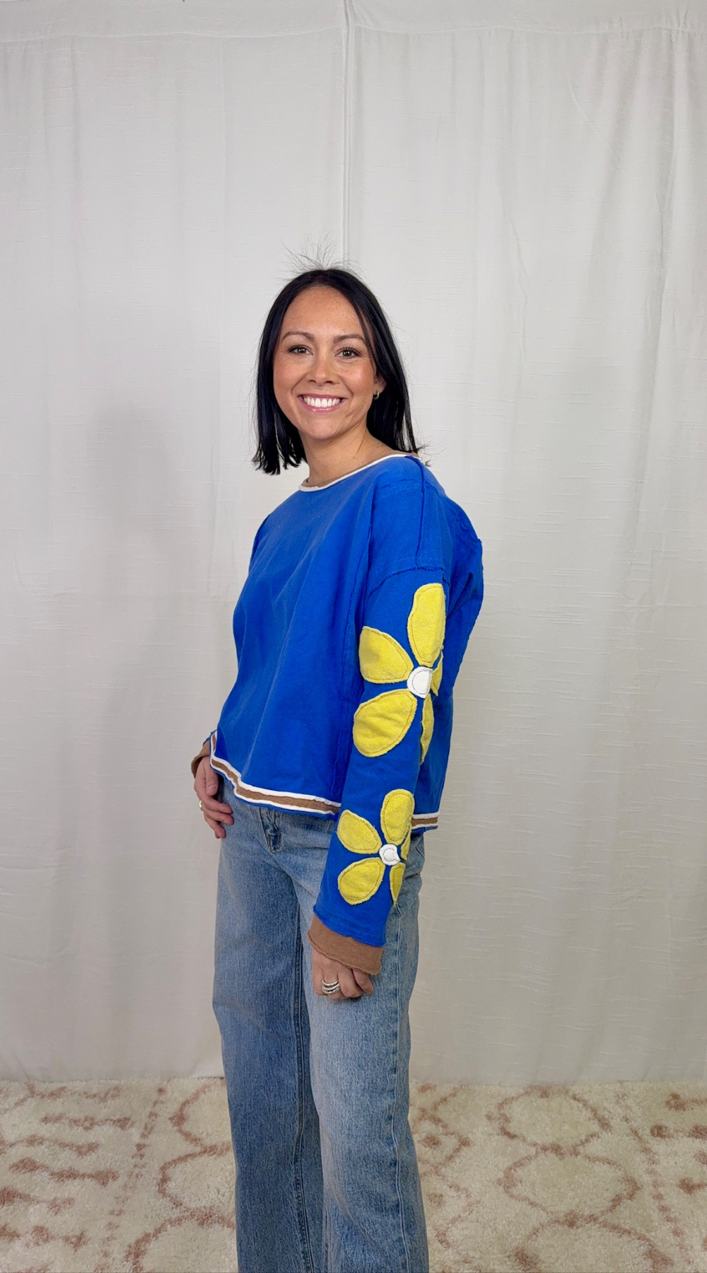 Blue long sleeve top with floral appliqué sleeves worn with blue jeans