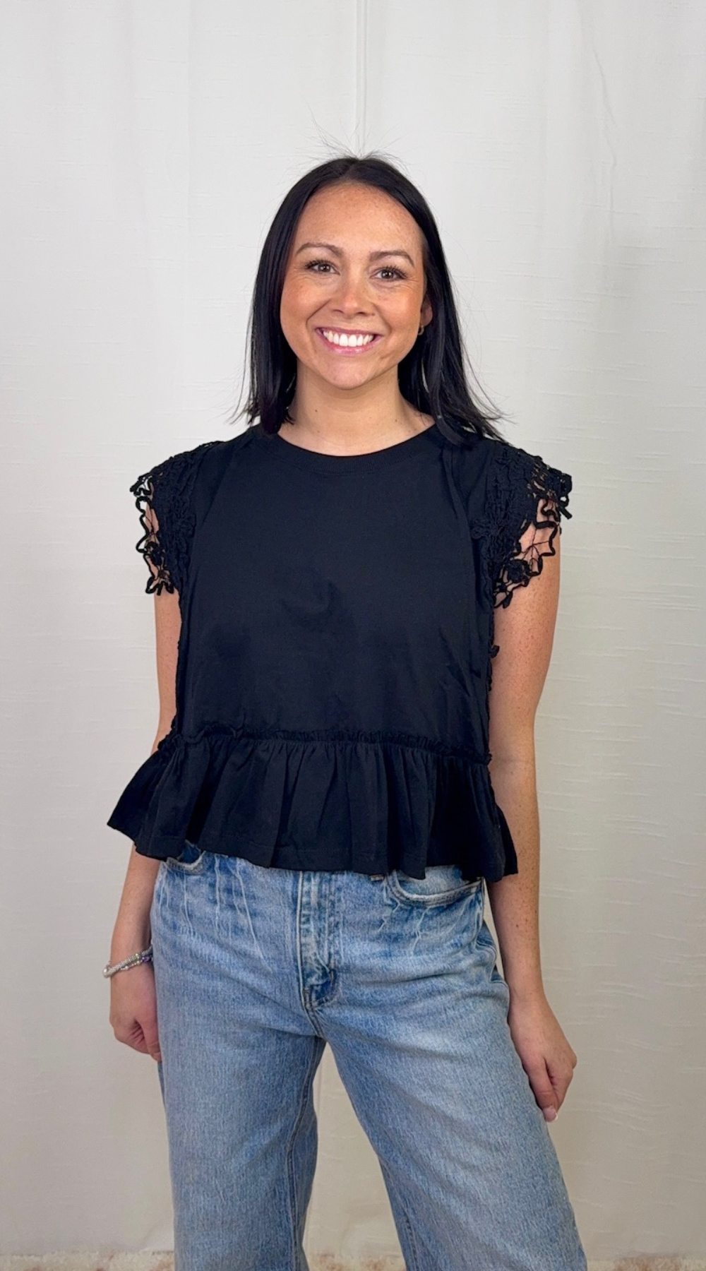 Black ruffle hem sleeveless cotton top worn with blue jeans