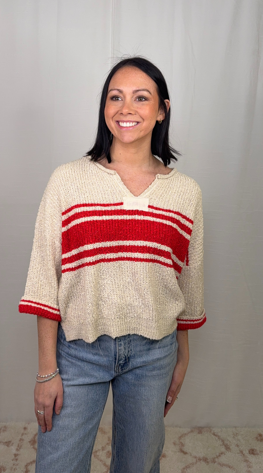 Cream knit striped sweater with red stripe detail worn with blue jeans