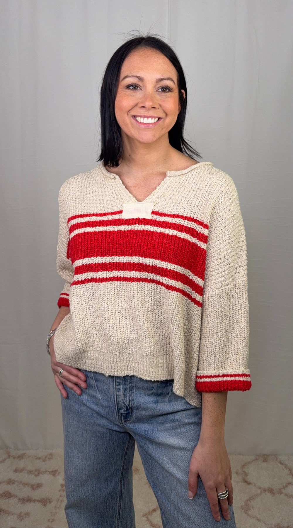 Cream knit striped sweater with red stripe detail worn with blue jeans
