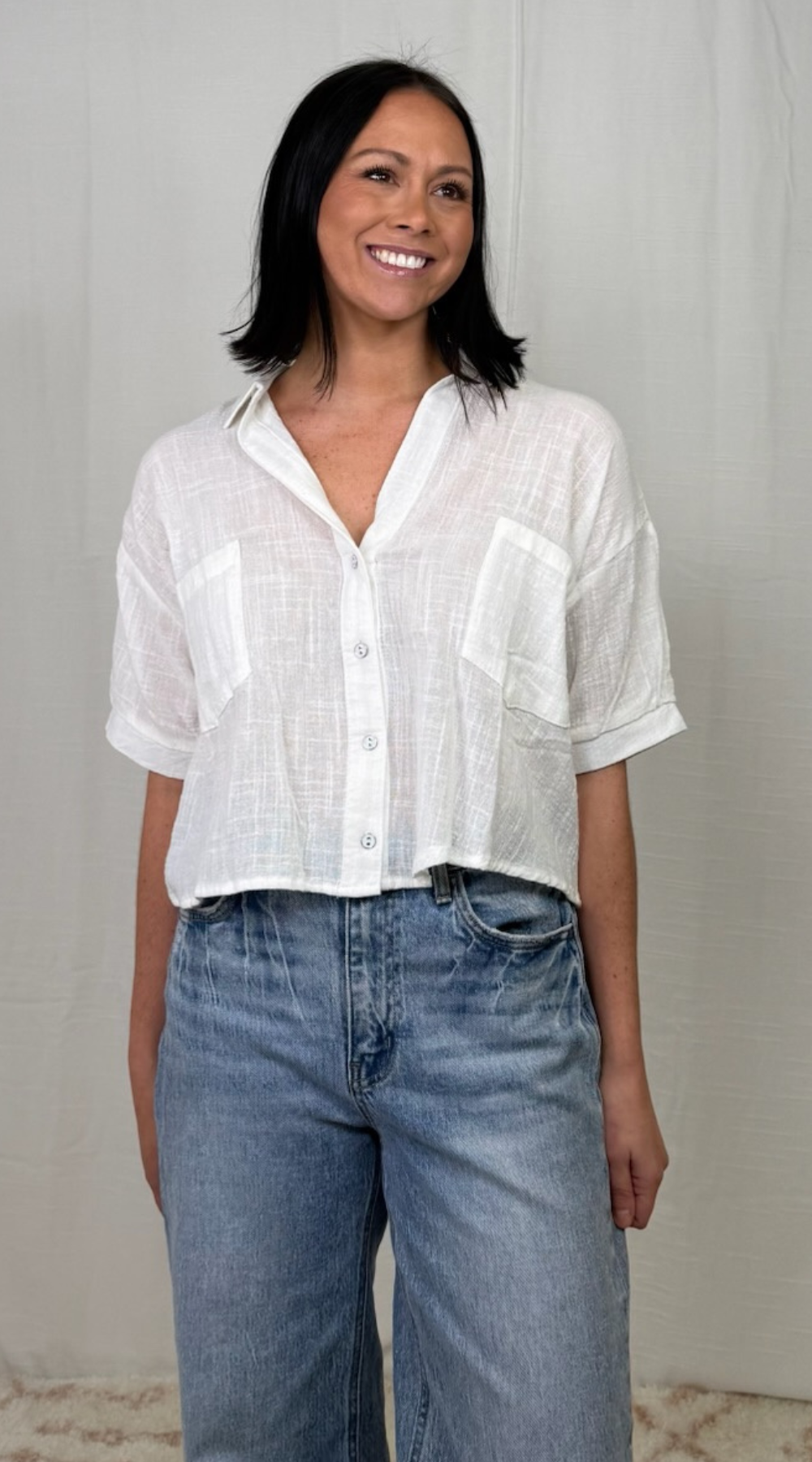 woman wearing white cotton button-down woven top with high-rise jeans
