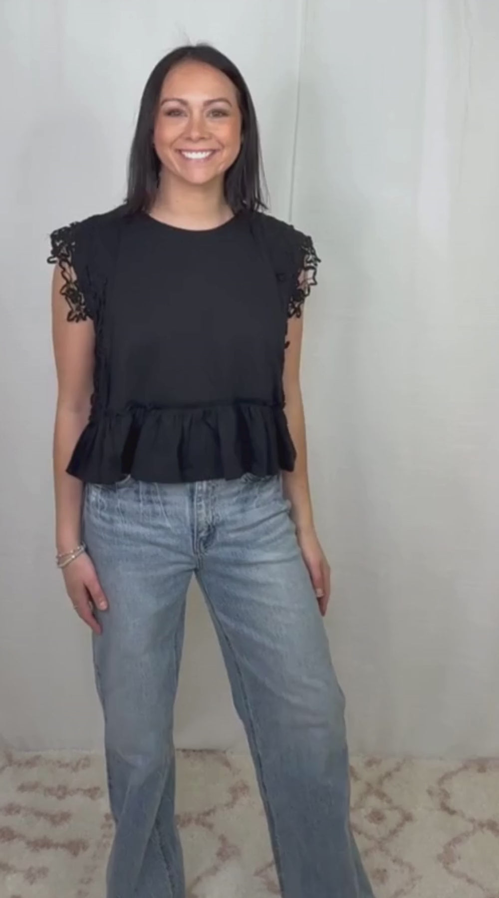 Black ruffle hem sleeveless cotton top worn with blue jeans