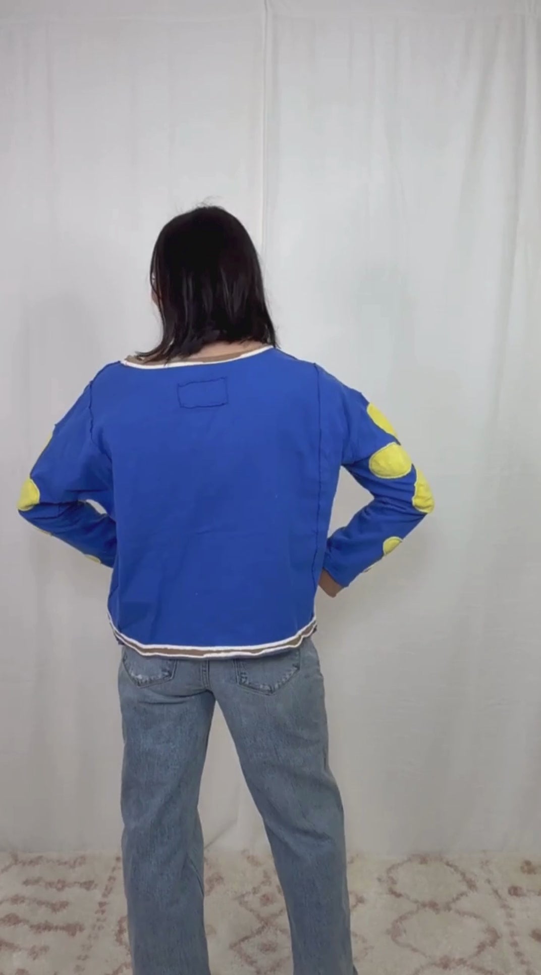 Blue long sleeve top with floral appliqué sleeves worn with blue jeans