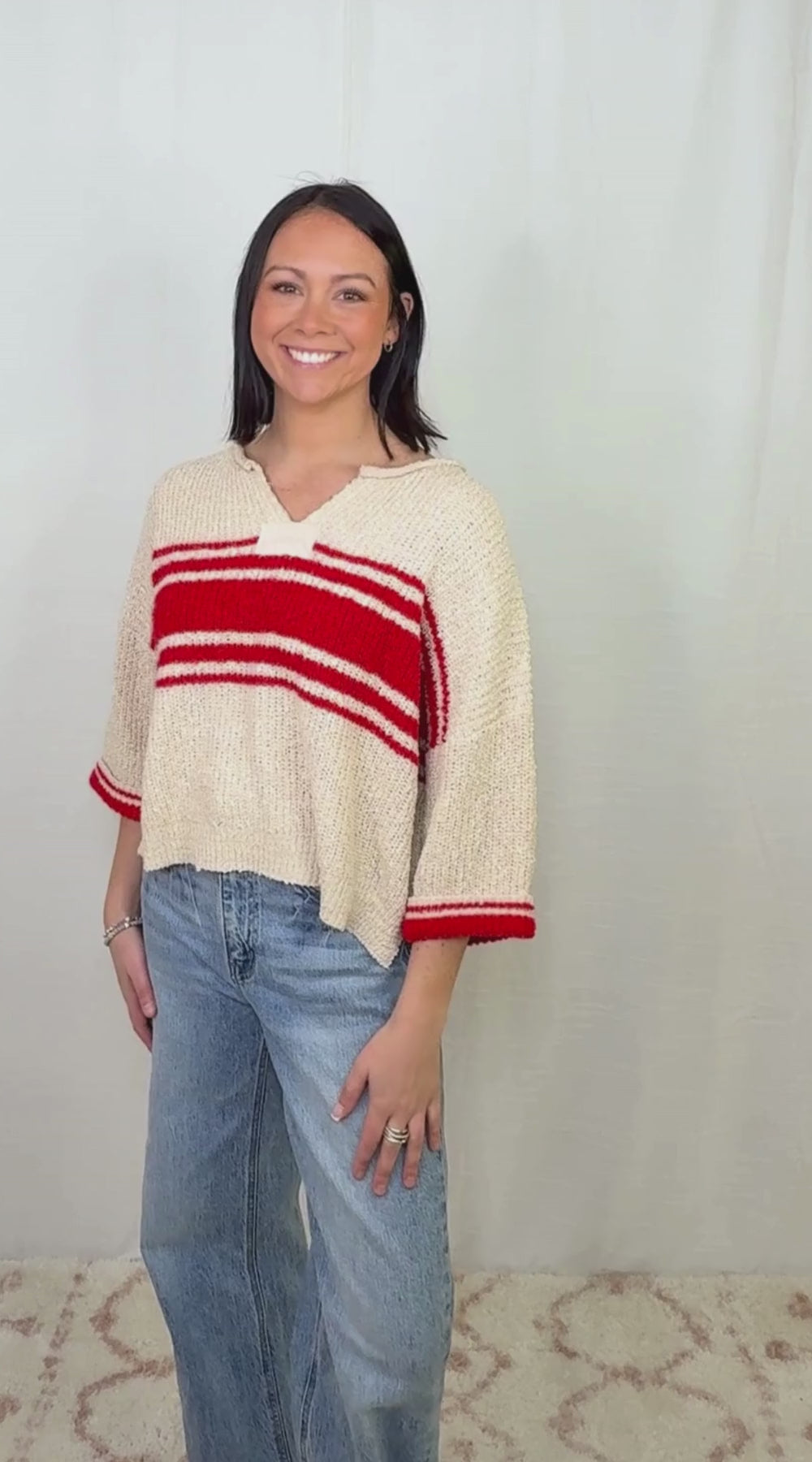 Cream knit striped sweater with red stripe detail worn with blue jeans